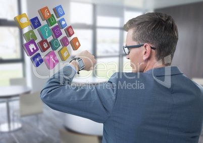 Businessman holding arm with watch and apps icons to eyes in office