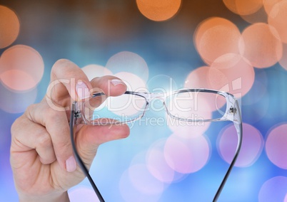 Hand holding glasses with sparkling light bokeh background