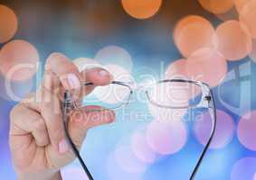 Hand holding glasses with sparkling light bokeh background