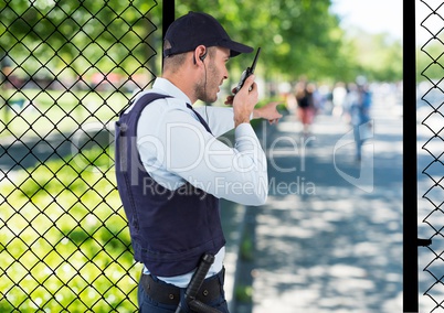 security guard of the park spiking with the walkie-talkie and point to something.