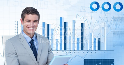 Digital image of businessman holding device while sitting against graphs