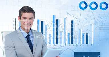 Digital image of businessman holding device while sitting against graphs
