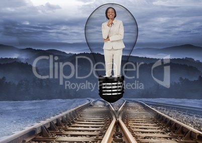 Digital image of businesswoman in bulb over railway tracks standing against mountains