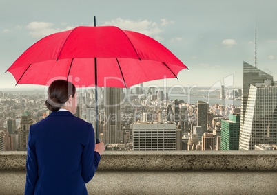 Rear view of businesswoman holding red umbrella while looking at city