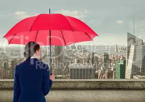 Rear view of businesswoman holding red umbrella while looking at city