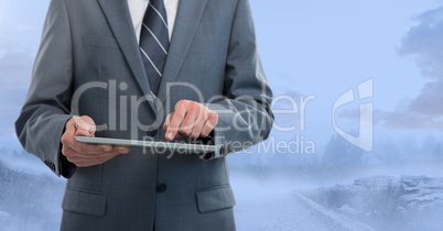 Businessman holding tablet outside in blue landscape