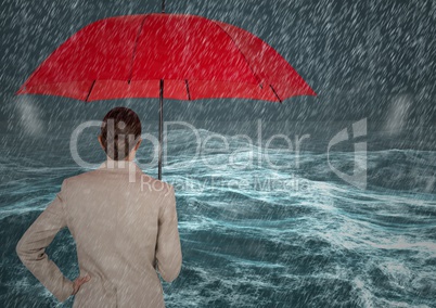 Back of business woman with umbrella against stormy sea with rain