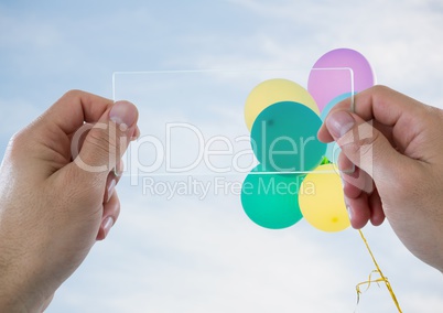 Hands with glass device against sunny sky with balloons