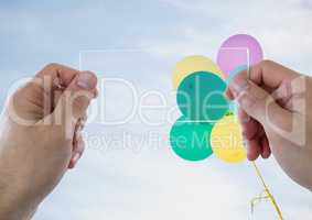 Hands with glass device against sunny sky with balloons