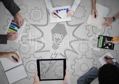 Overhead of business team writing on grey surface with lightbulb and cog graphics