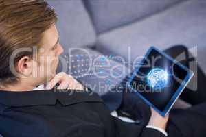 Businessman sit down is watching tablet computer against grey background