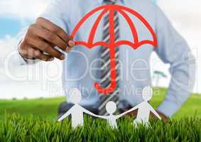 Cut out umbrella protecting family on grass