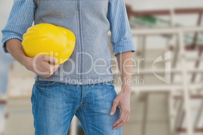 Worker holding a yellow helmet against construction