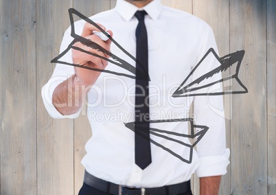 Business man mid section writing airplane doodles against grey wood panel