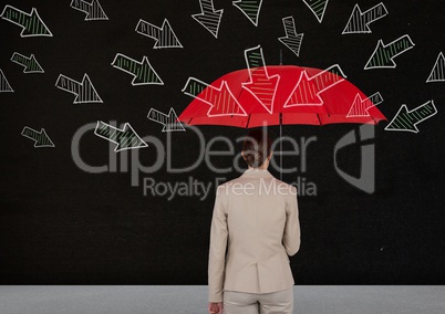 Rear view of businesswoman standing against blackboard holding red umbrella with arrows pointing