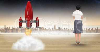Digital composite image of businesswoman looking at rocket launch against city