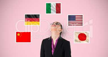 Businesswoman looking up while standing by flags against pink background