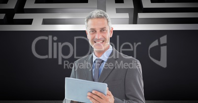 Businessman holding digital tablet while standing against maze