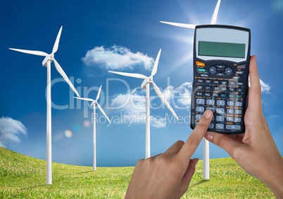 Hands holding calculator on wind farm against sky