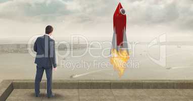 Rear view of businessman standing by rocket launch while looking at sea