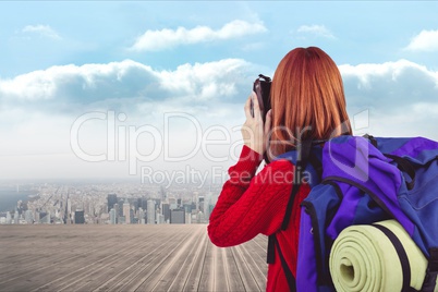 traveler carrying bag is taking photo against cityscale background