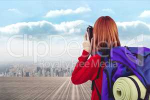 traveler carrying bag is taking photo against cityscale background