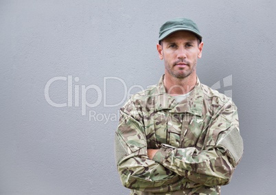 serious soldier with his hands folded. concrete wall behind
