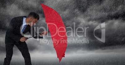 Business man blocking rain with umbrella against storm clouds