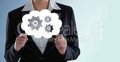 Business woman mid section with glass device behind white cloud and gear graphic against blue backgr