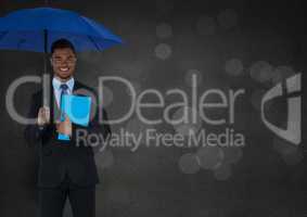 Business man with umbrella and blue book against grey wall and bokeh