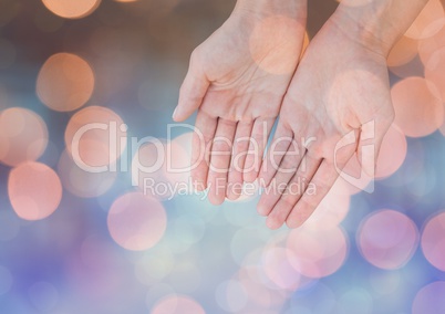 Hands open gently with sparkling light bokeh background