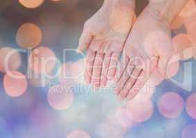 Hands open gently with sparkling light bokeh background