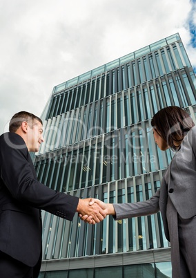 business man and woman handshake in front of the building