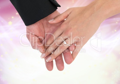 Hands holding together wedding engagement ring with sparkling light bokeh background