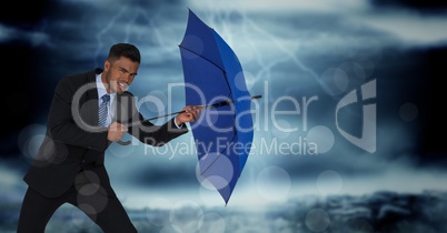 Business man with umbrella blocking wind against stormy sky and bokeh