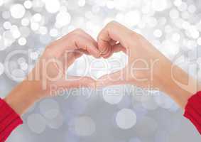 Hands in heart shape with sparkling light bokeh background