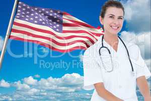 doctor wearing white coat and stethoscope in front of american flag against sky background