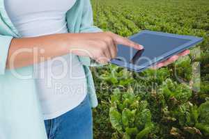Woman model touching tablet computer screen against field