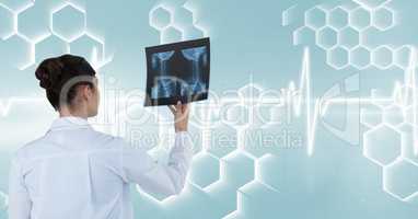 Rear view of female doctor holding x-ray report against interface