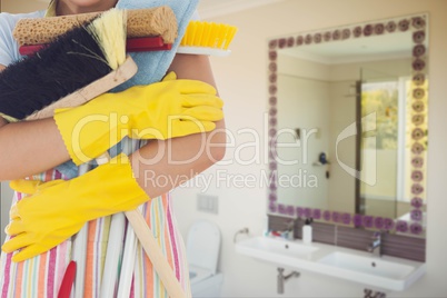 Cleaner wearing washing up gloves and an apron holding broom against bathroom background