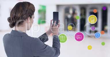 Businesswoman holding mobile phone with apps  in shopping mall