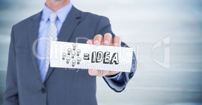 Business man mid section with card showing  grey idea doodle against blurry blue wood panel