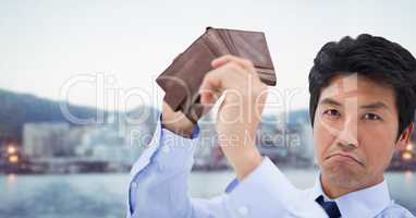 Sad businessman with his wallet empty and city background to show empty pockets concept