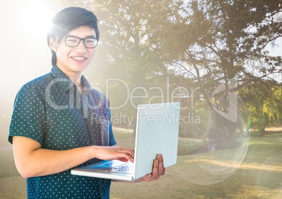 Trendy man with laptop against blurry park with flares