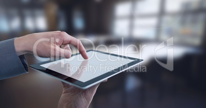 Businessman touching tablet in wide room towards windows