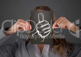 Business woman with black card over face showing white thumbs up doodle against grey background