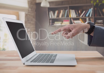 Businessman pointing at laptop with bookshelf Businessman pointing at laptop with bookshelf