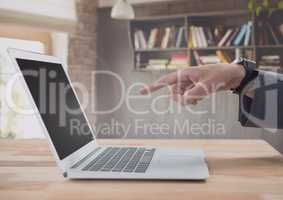 Businessman pointing at laptop with bookshelf