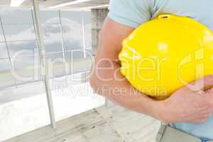 Architect holding a yellow safety helmet against room background
