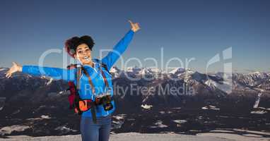 Hipster cheering with arms outstretched standing against mountains